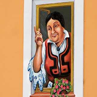 Venkovní malba na zdi společnosti CH Kovo s motivem paní v okně